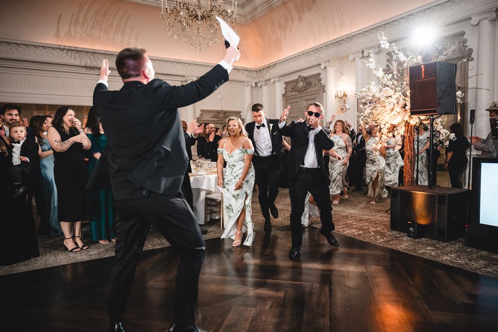 Energetic wedding reception entrance with sparklers and cheering guests on dance floor.