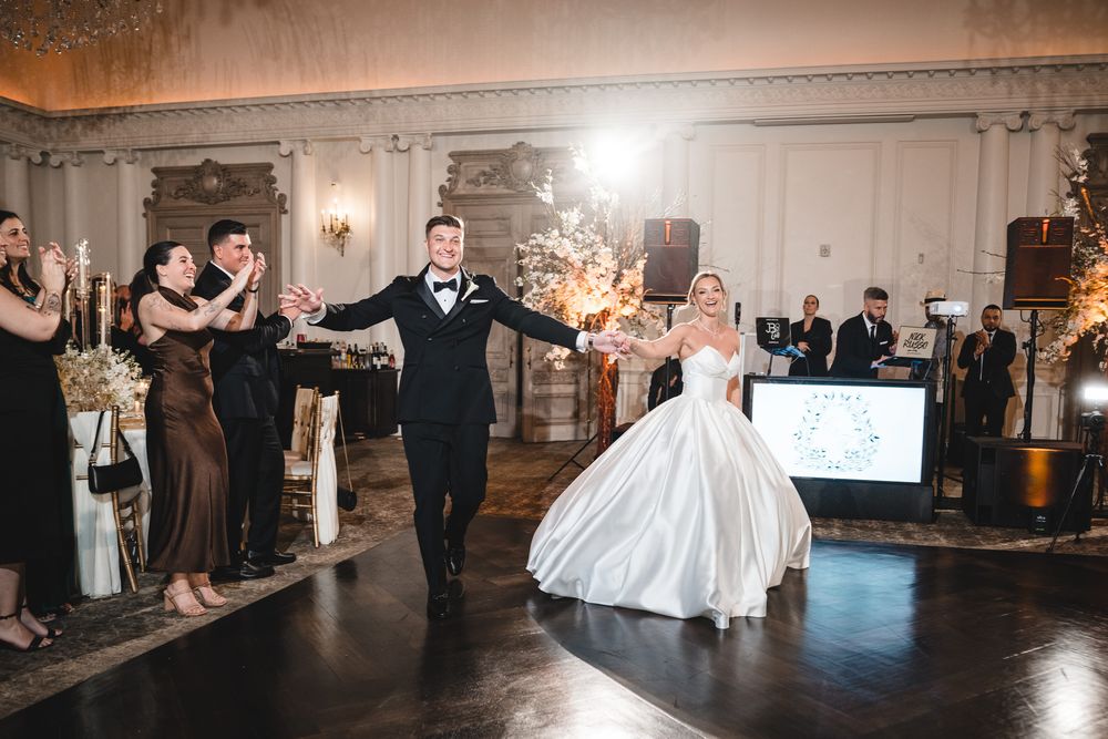 Newlyweds make a grand entrance onto the dance floor surrounded by cheering guests and sparkling lights.