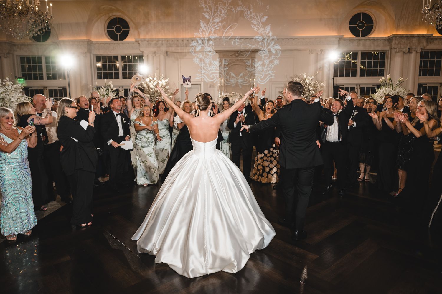 Bride in ballgown and groom celebrated by guests with sparklers at wedding reception.