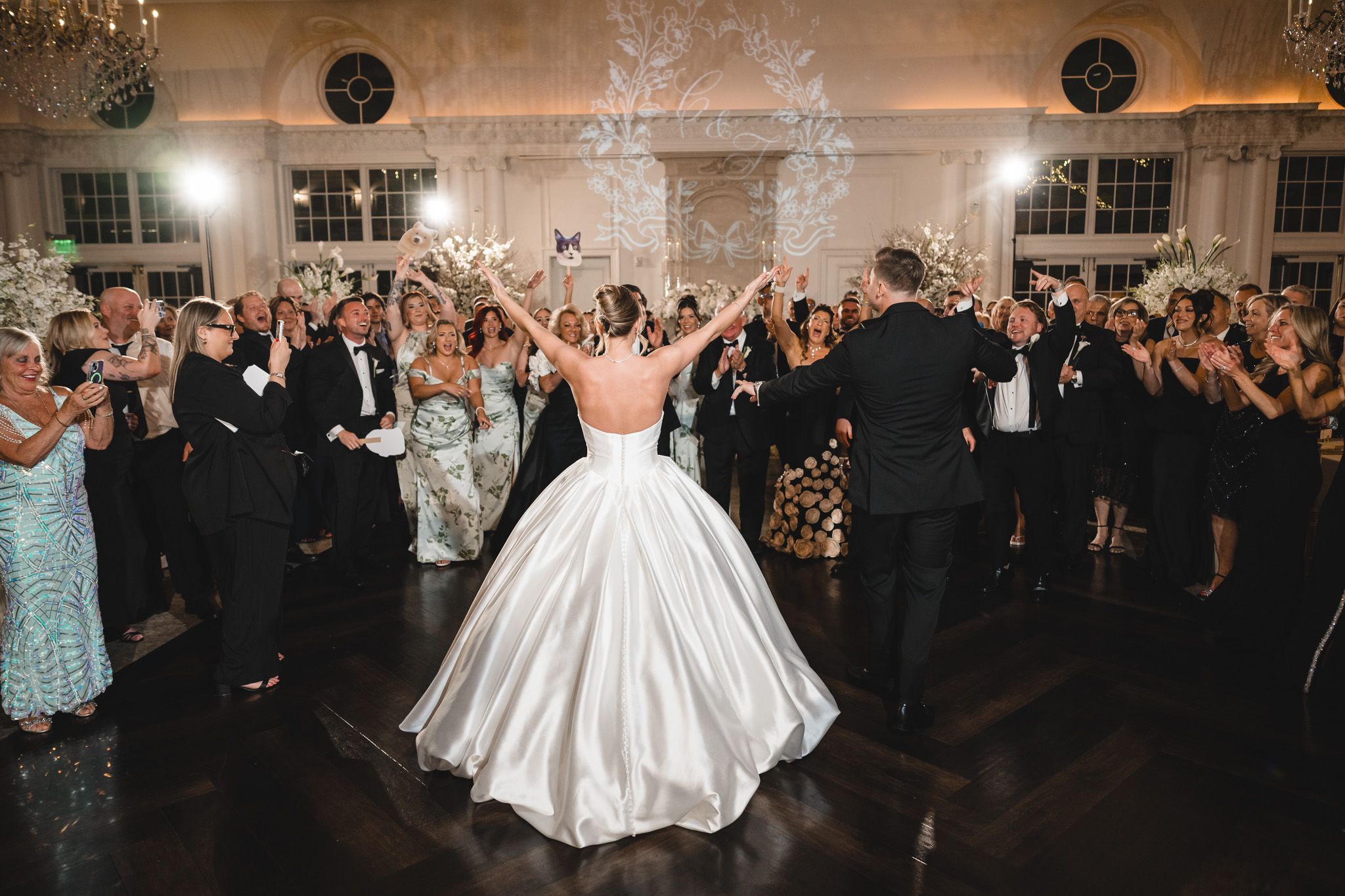 Bride in ballgown and groom celebrated by guests with sparklers at wedding reception.