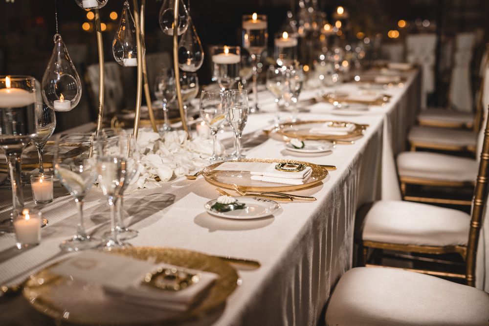 Luxurious wedding reception table set with gold chargers, crystal glassware, and candlelight.