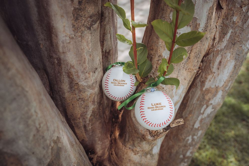 Two personalized baseball ornaments hanging in tree branches as unique wedding decorations or favors.