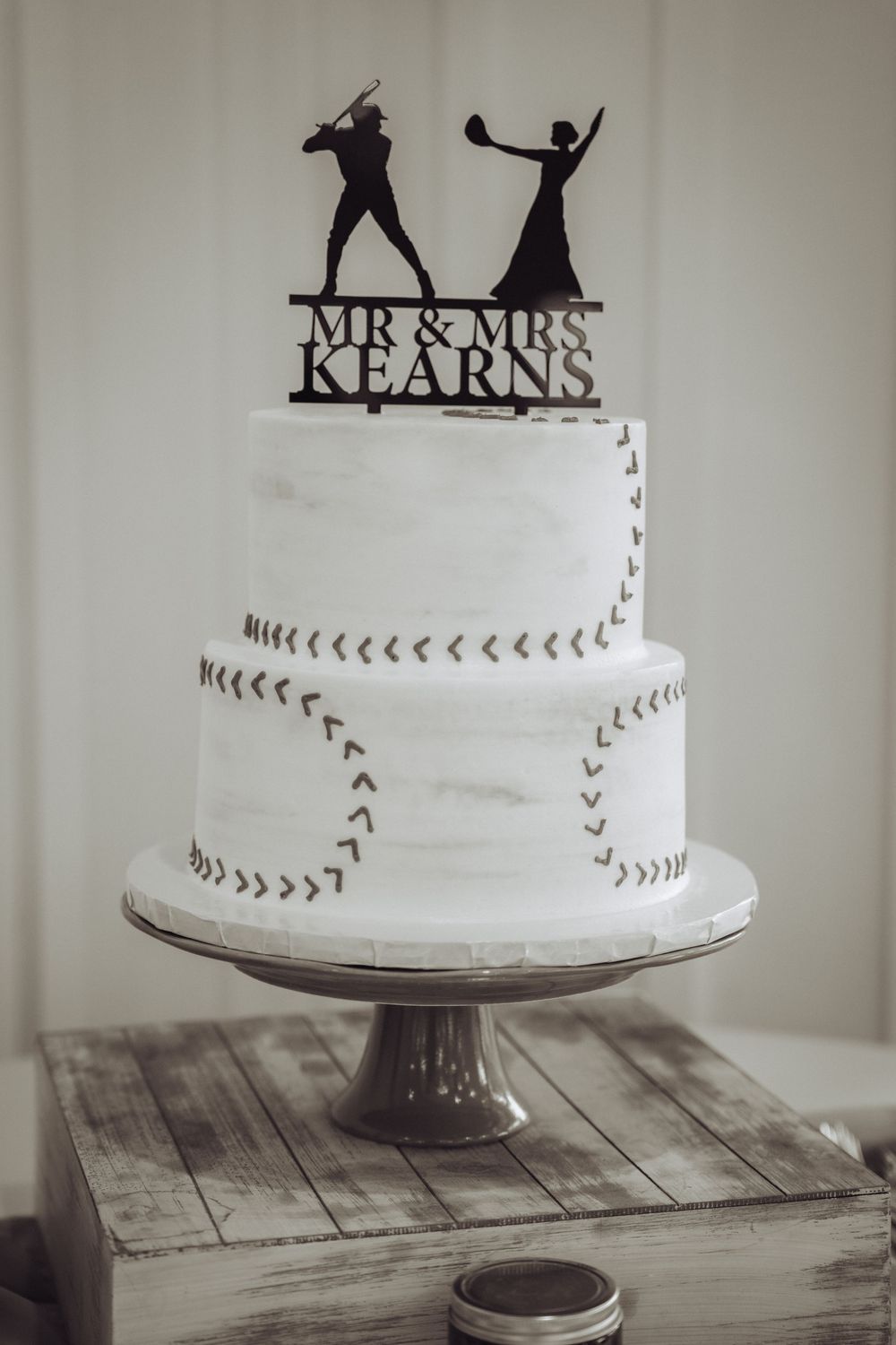 Baseball-themed two-tier white wedding cake for Mr & Mrs Kearns with silhouette topper on rustic cake stand.