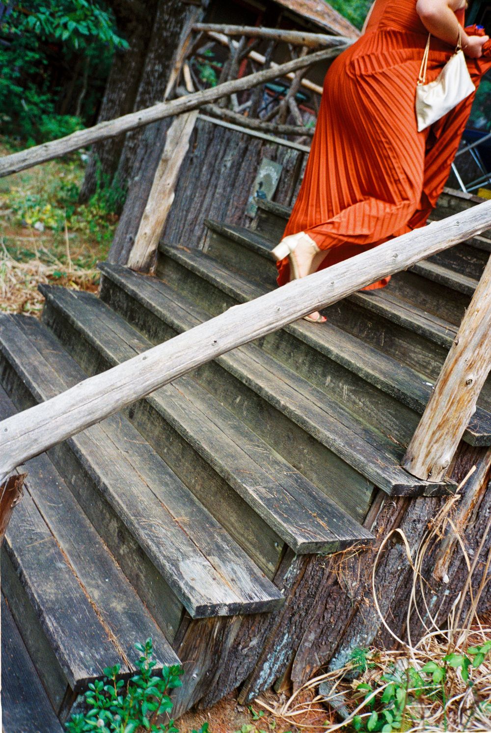 The maid of honor in her rust orange dress climbs the wooden stairs of the bride's family camp cottage before attending the wedding ceremony