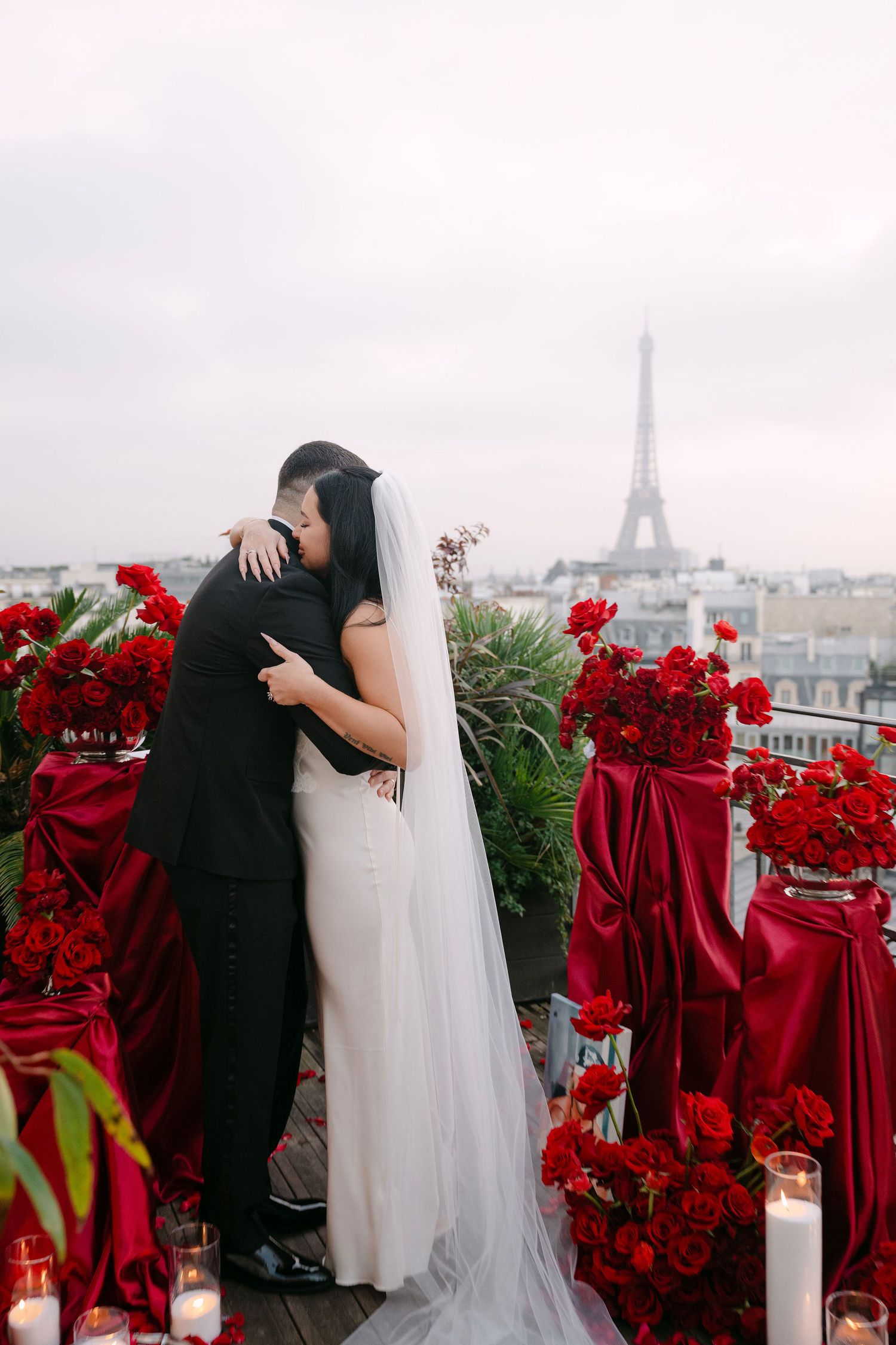 A romantic wedding moment in Paris with the Eiffel Tower visible in the background and vibrant red roses in the foreground.
