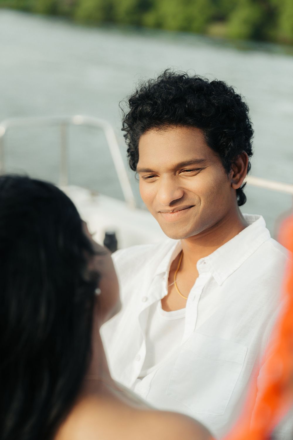 A romantic couple shares tender moments on a boat during a sunny day.