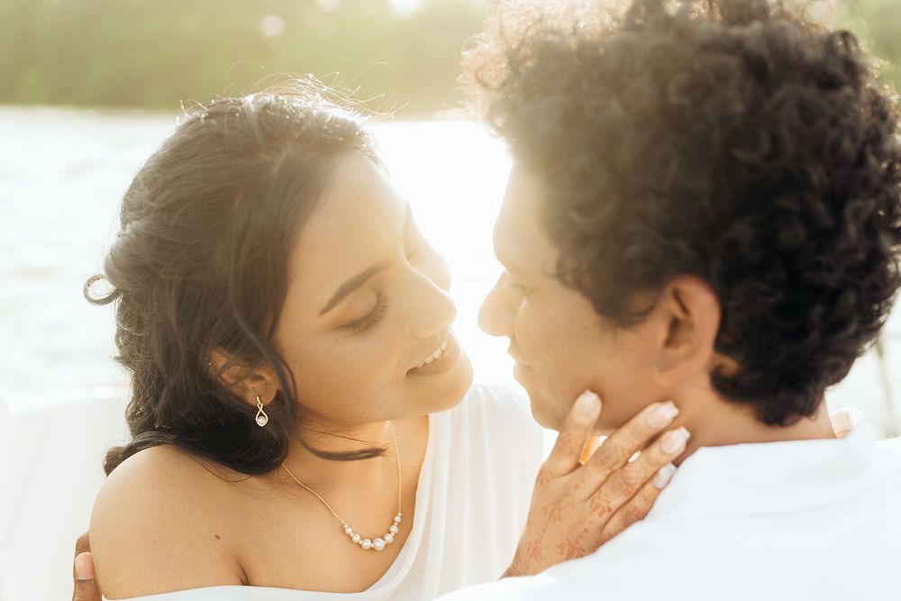 A romantic couple shares an intimate moment together in soft sunlit glow against a white background.
