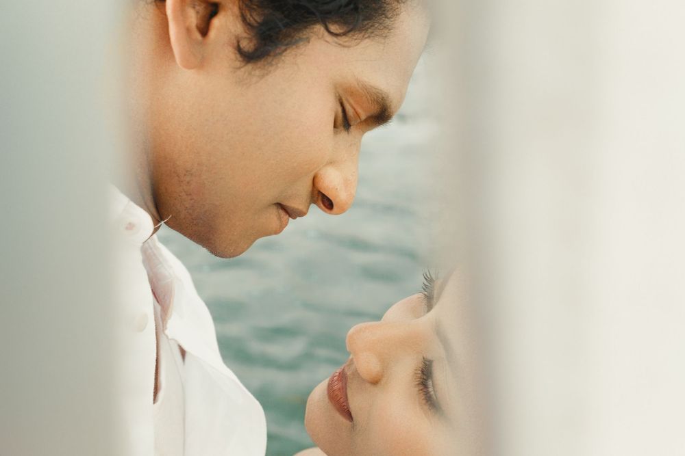 Two people share an intimate moment while embracing near water with soft lighting and romantic atmosphere.