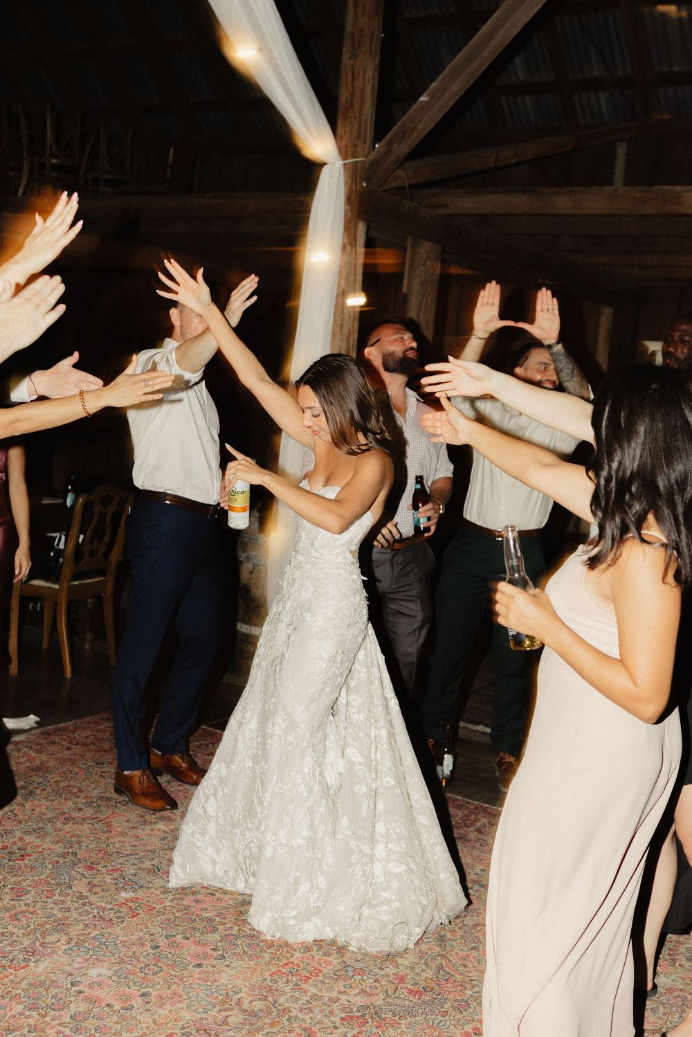 Wedding guests dancing and celebrating at a rustic barn reception.