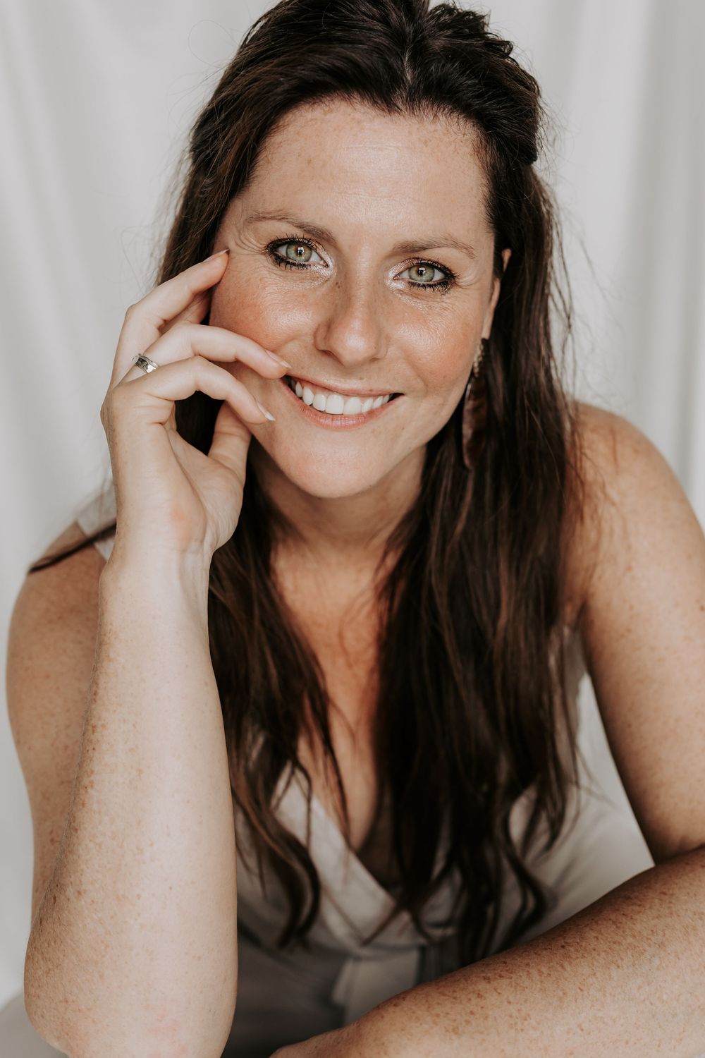 Close-up portrait of smiling woman with freckles and green eyes.