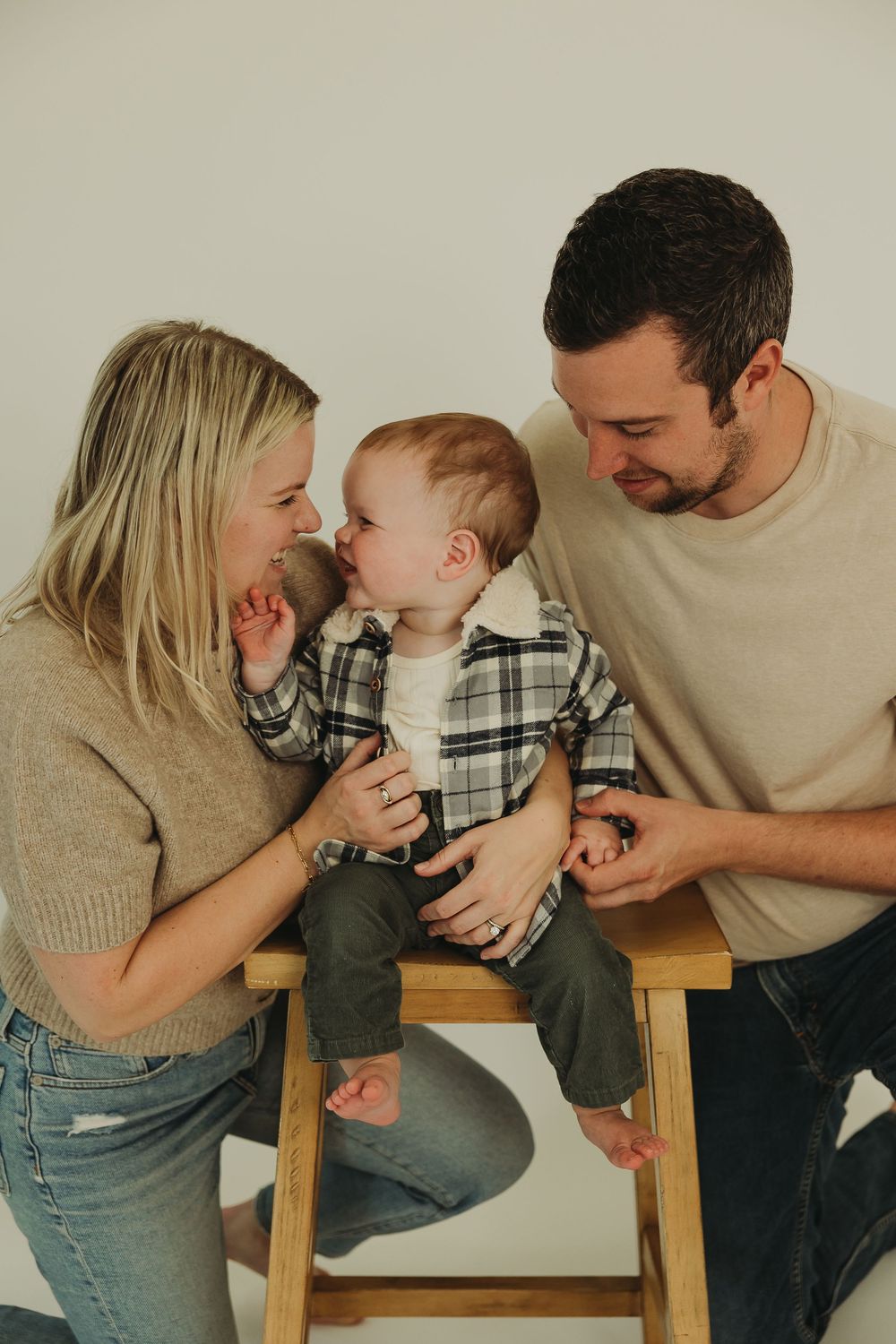 A family of three shares tender moments together while sitting on a wooden bench in a series of candid photos.