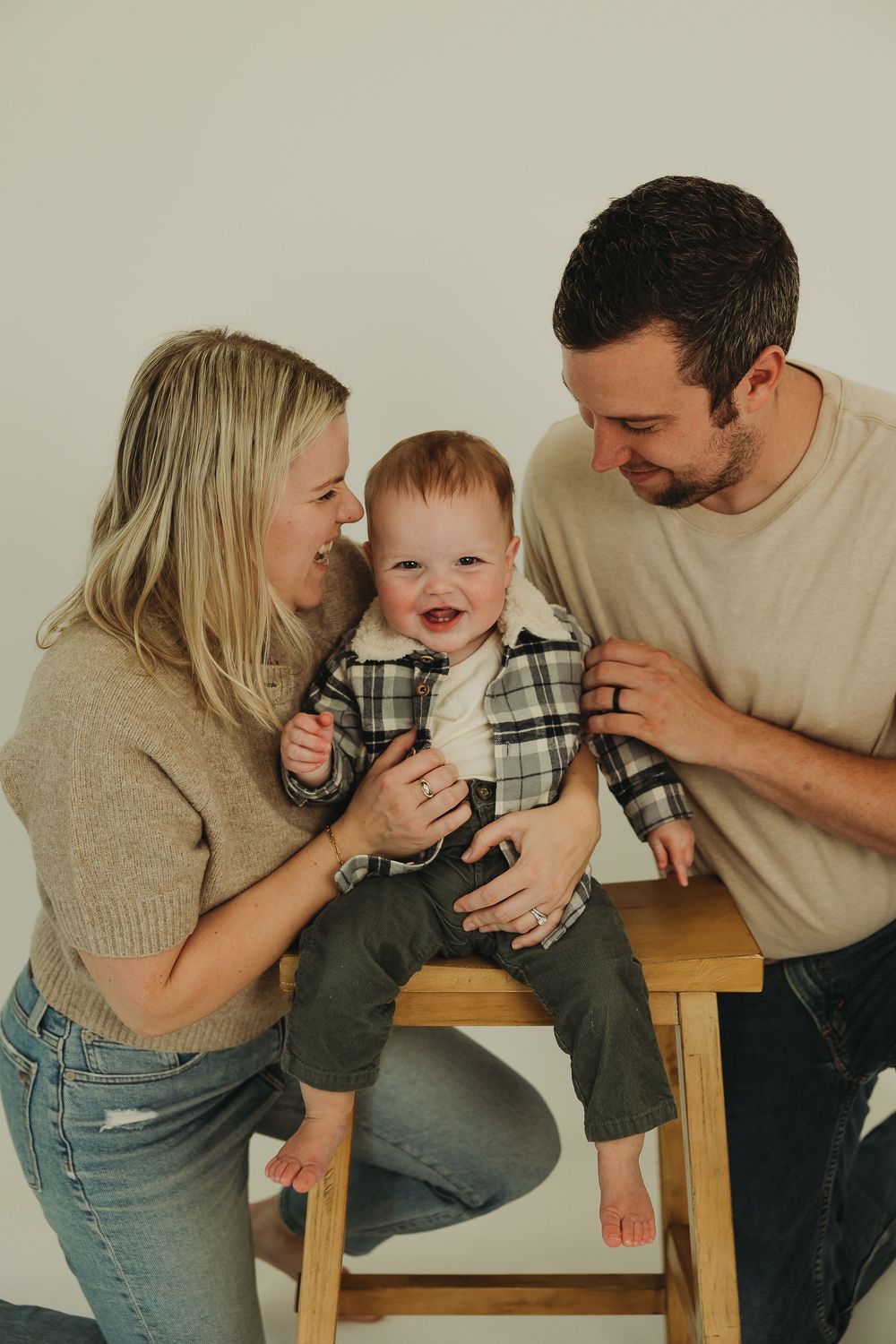A family shares a joyful moment together on a wooden bench, playing and laughing in a candid photo series.