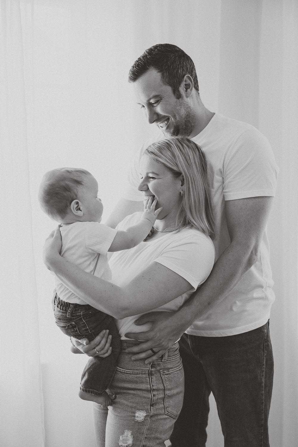A series of black and white photos showing tender family moments between parents and baby.