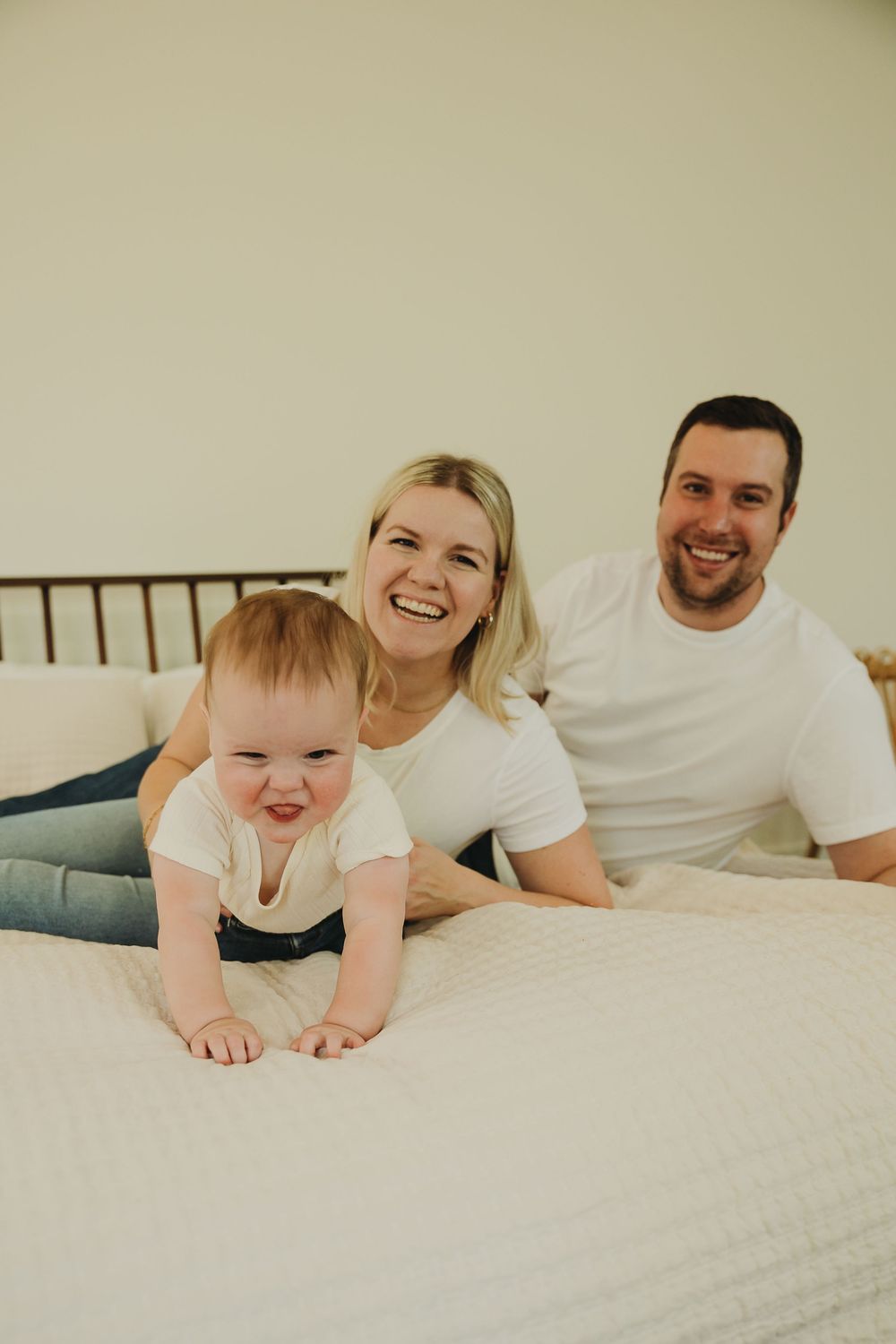 A series of candid moments showing a baby and parent lying together on white bedding.