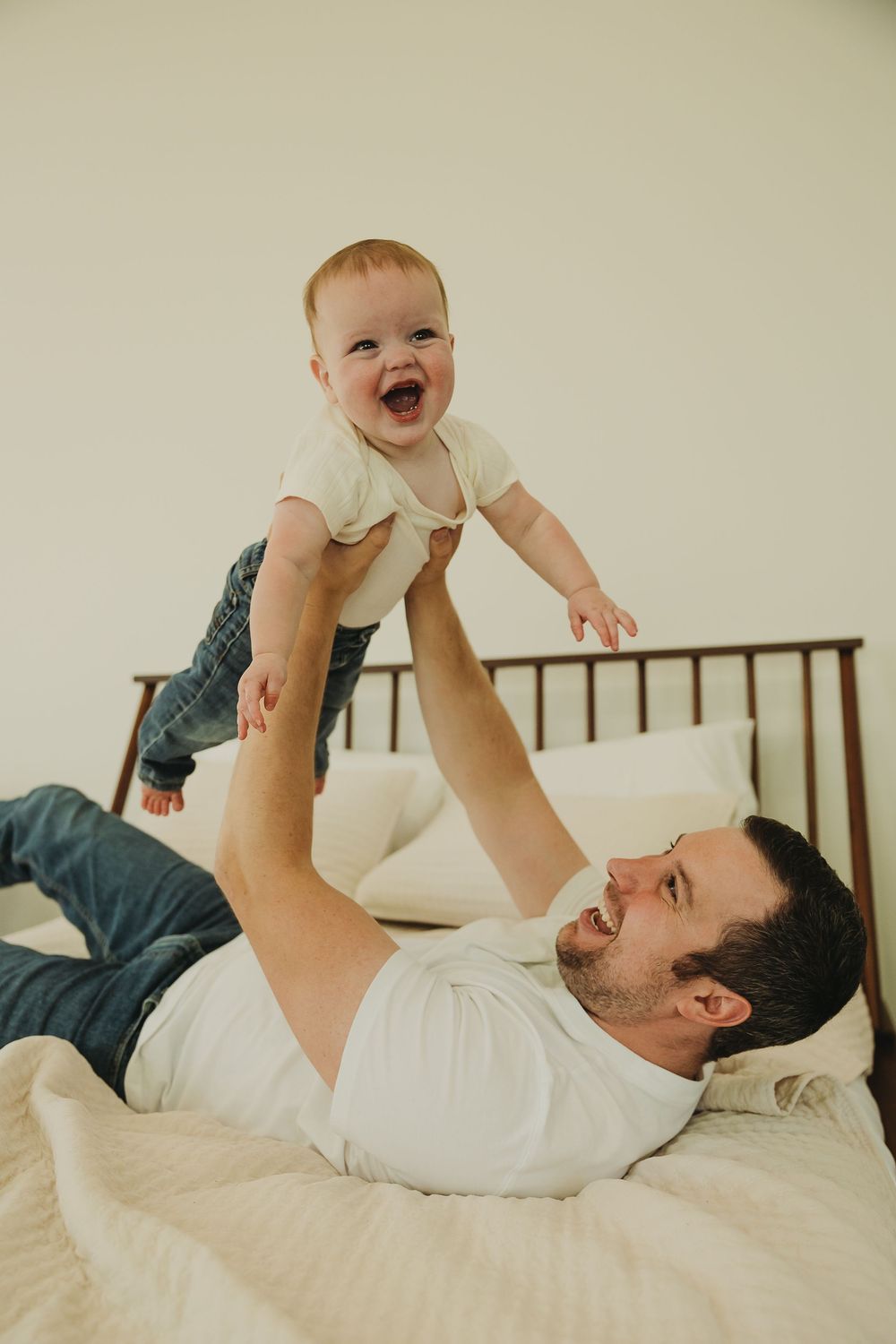 A heartwarming scene of parent-child bonding as they share laughter while playing on a bed.