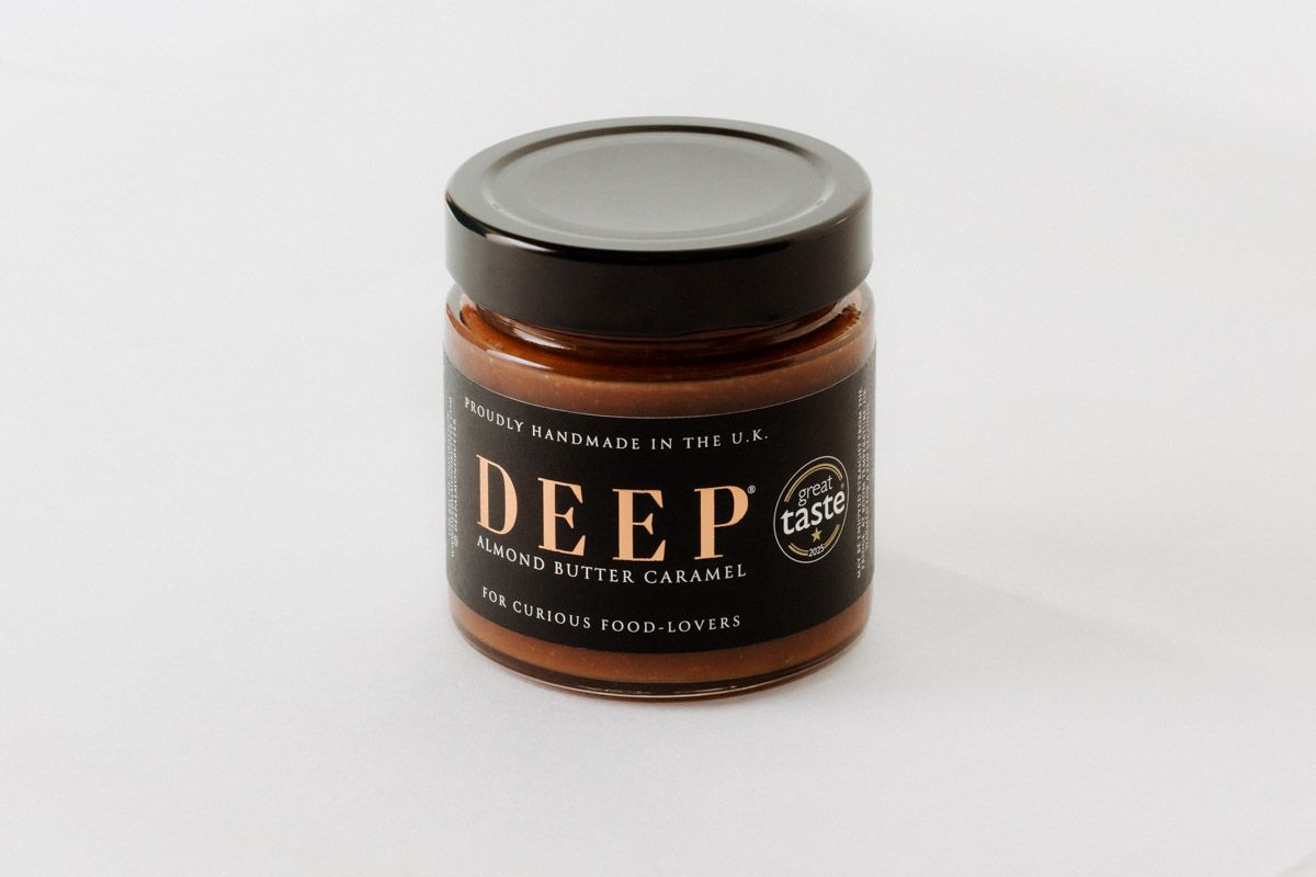 Jar of artisanal almond butter product against white background.