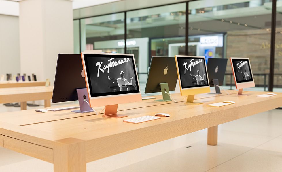 Minimalist retail display at Apple Store, with wooden tables and colourful iMac computers.