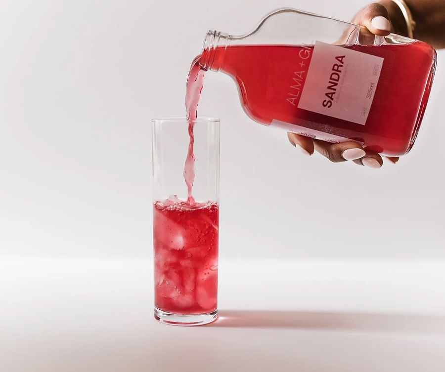 Red beverage being poured between clear glasses creating a dynamic splash effect.