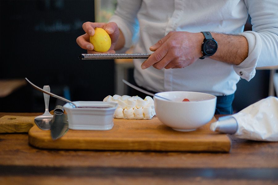 Hands preparing ingredients on a wooden cutting board in a professional kitchen setting.
