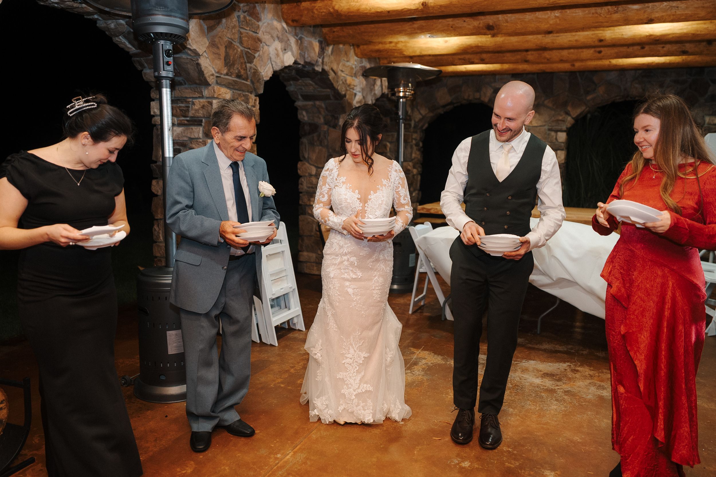 People dancing and celebrating on a rustic wooden dance floor at a wedding reception.