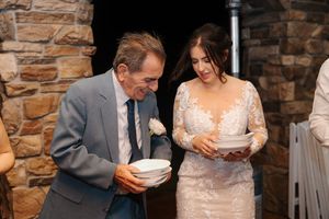 A couple shares a meal together at a rustic stone-walled venue during a wedding celebration.