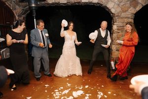 Wedding guests dance and celebrate on a rustic stone-walled dance floor at an evening reception.
