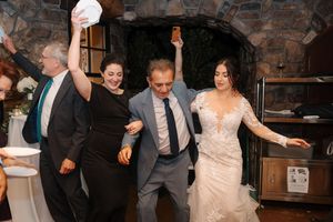 Wedding guests dance and celebrate together on a rustic stone-walled dance floor during a reception party.