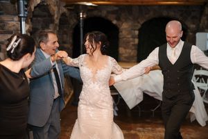 Wedding guests dance and celebrate together on a rustic dance floor at an evening reception.