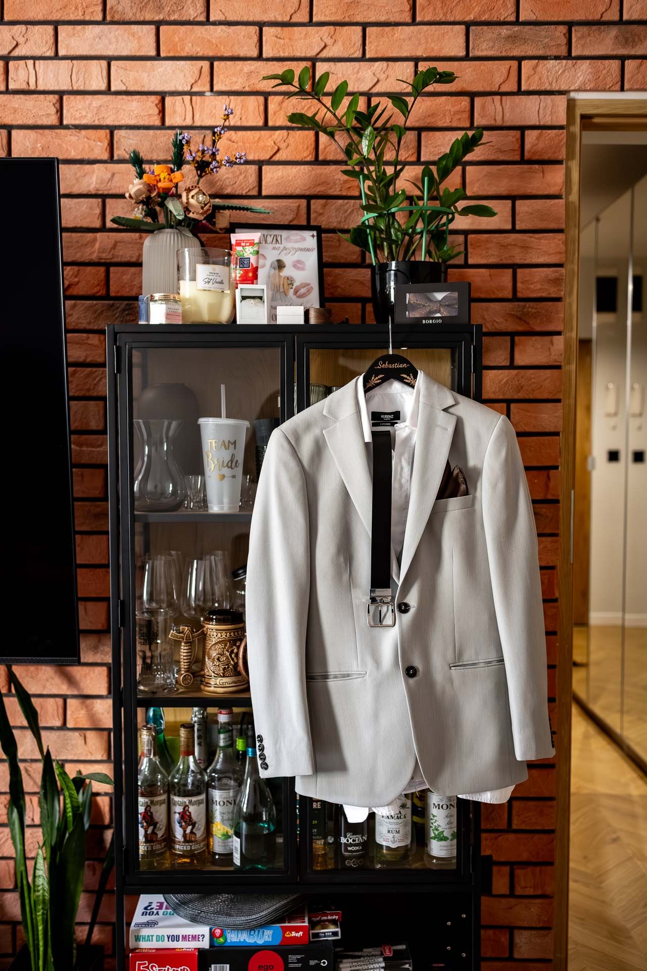 White formal jackets displayed on a bar cart against exposed brick wall with glassware.