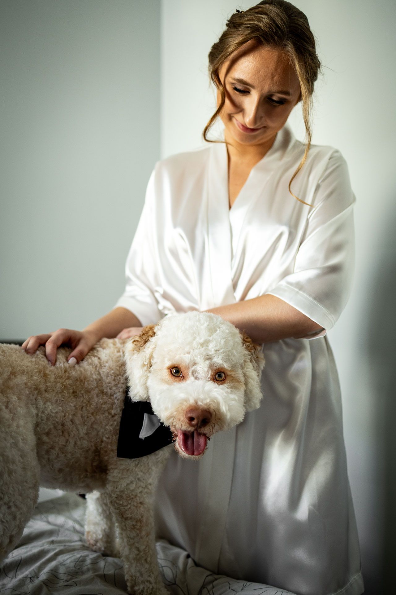 Person in white robe petting a fluffy white dog on a couch.