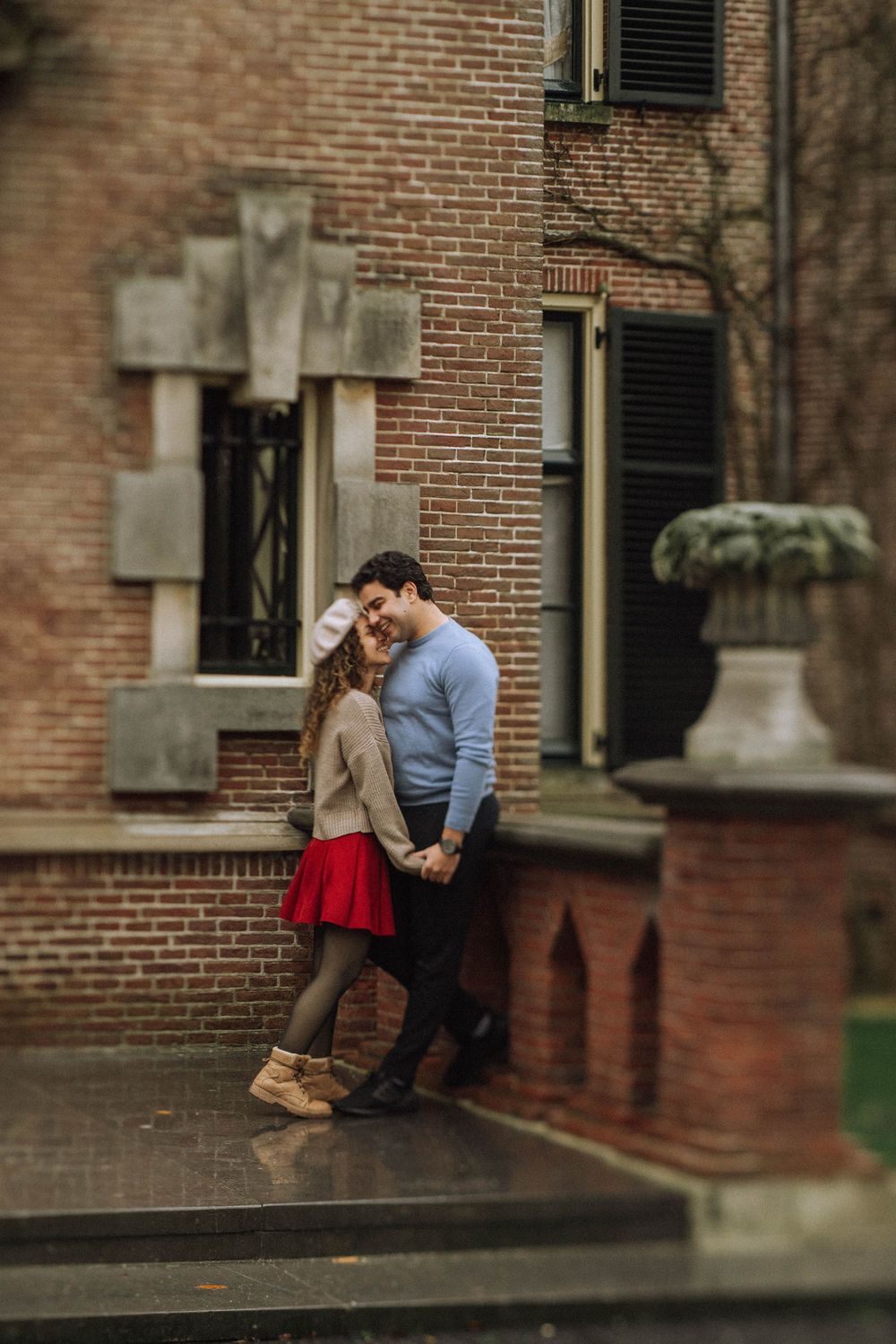 A romantic couple shares an intimate moment against a brick of Koukenhof castle.