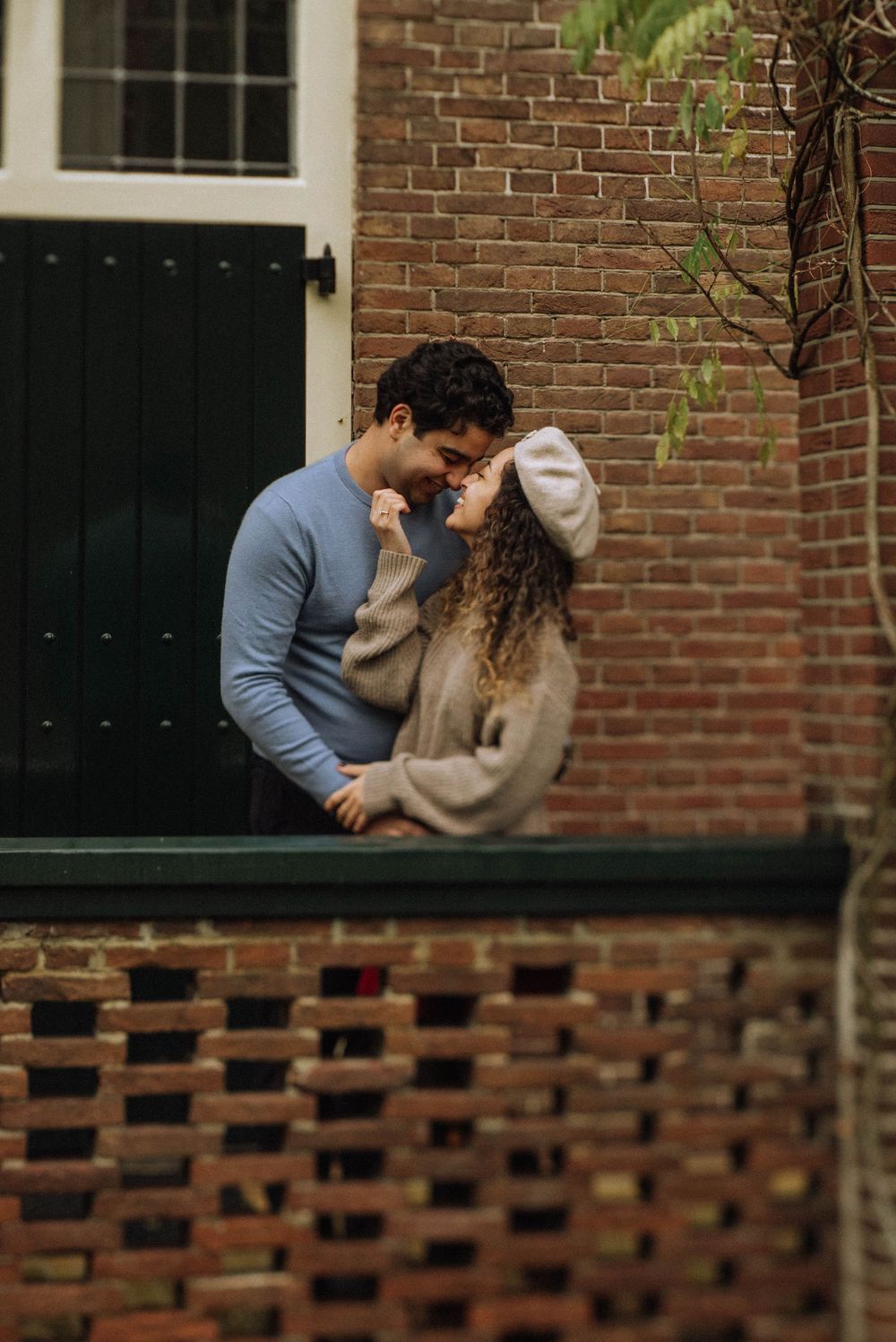 A romantic moment shared between a couple against a brick wall background with decorative brickwork details.