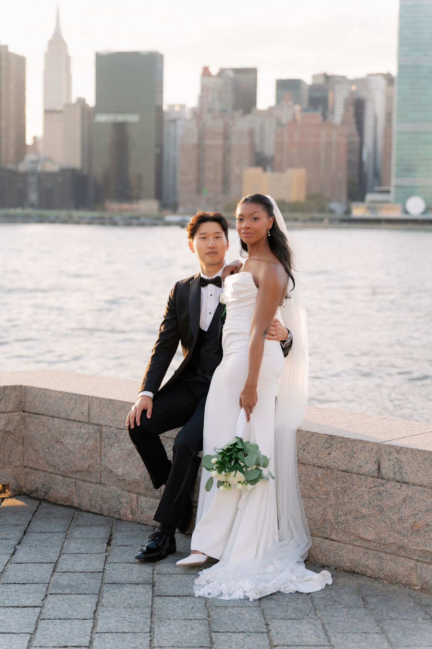 Waterfront wedding photos with Manhattan skyline backdrop during sunset.