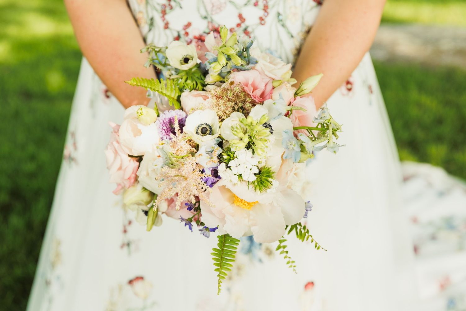 Close-up of delicate pink and white floral wedding bouquet with mixed flowers and greenery.