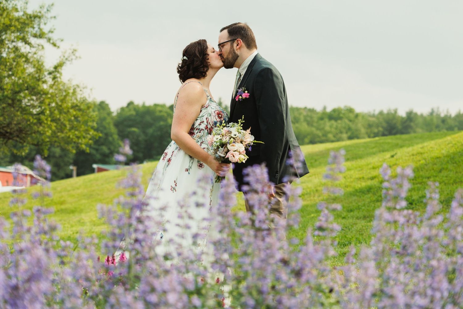 Newlyweds share an intimate moment in a meadow filled with purple lupine flowers.