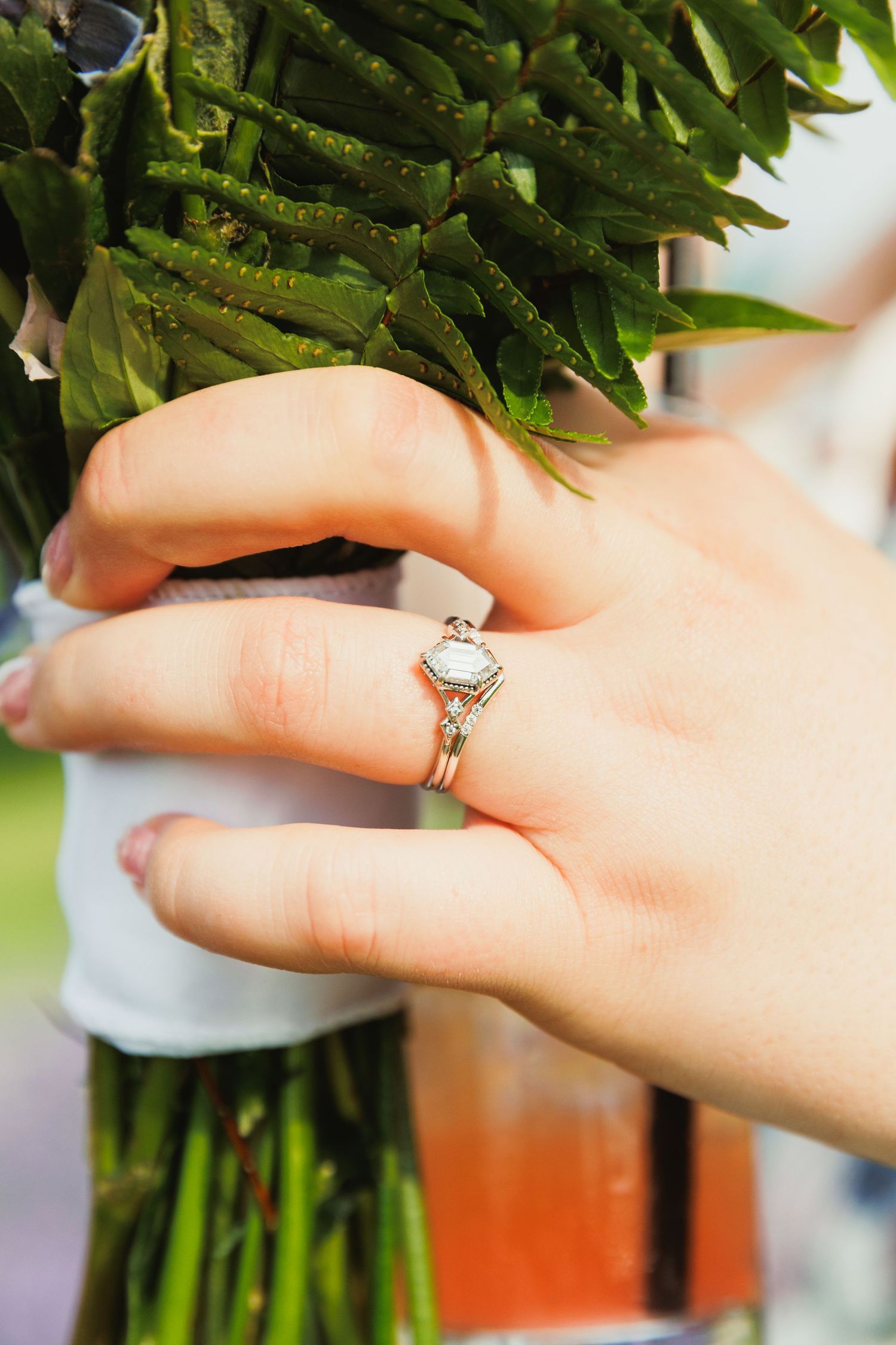 Close-up of an engagement ring on a hand holding a fresh bouquet of flowers.