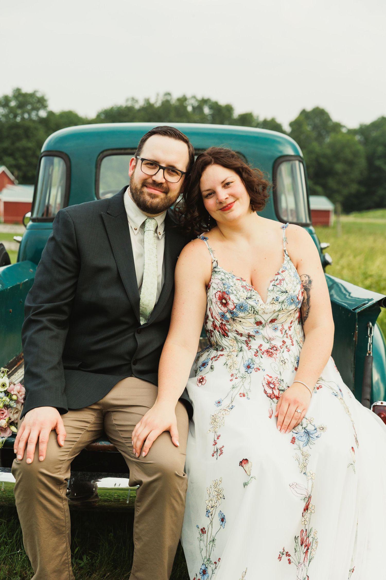 Wedding couple poses together in front of a vintage teal truck for their countryside photos.