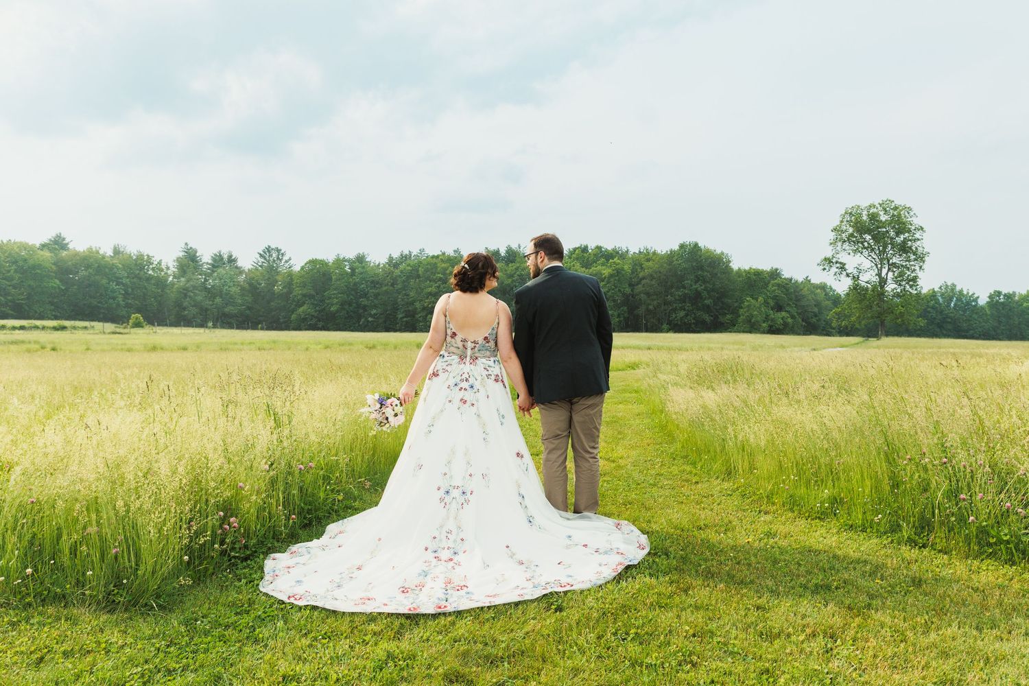 A romantic wedding photo session in a golden summer field with rolling hills in the background.