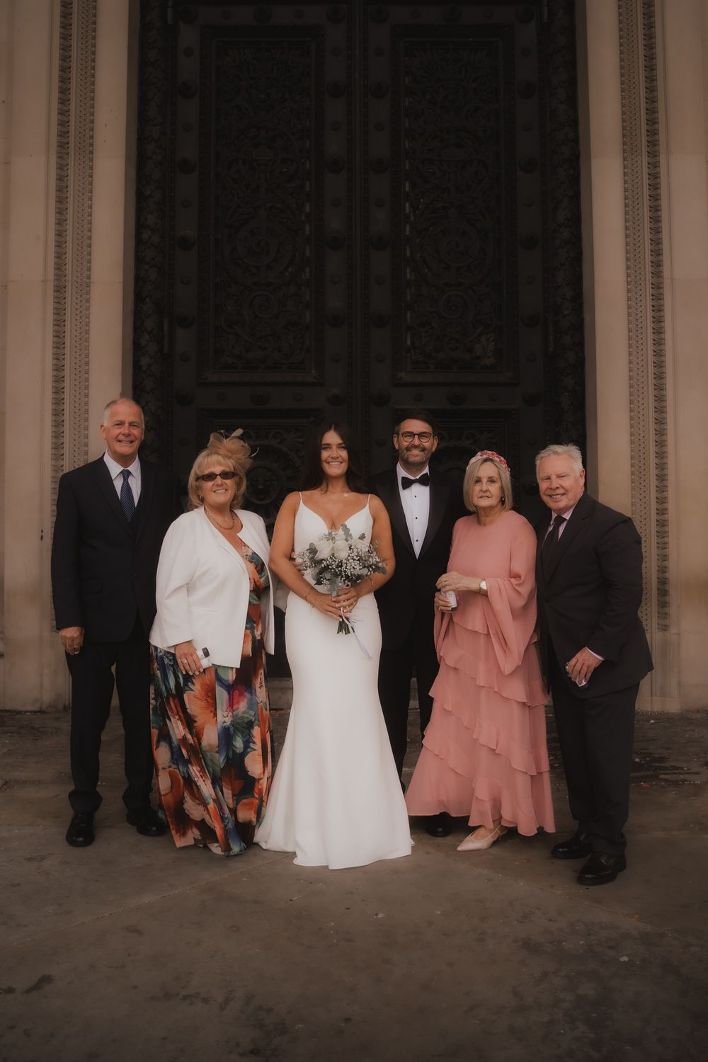 Wedding party members line up against an elegant backdrop for formal portraits.