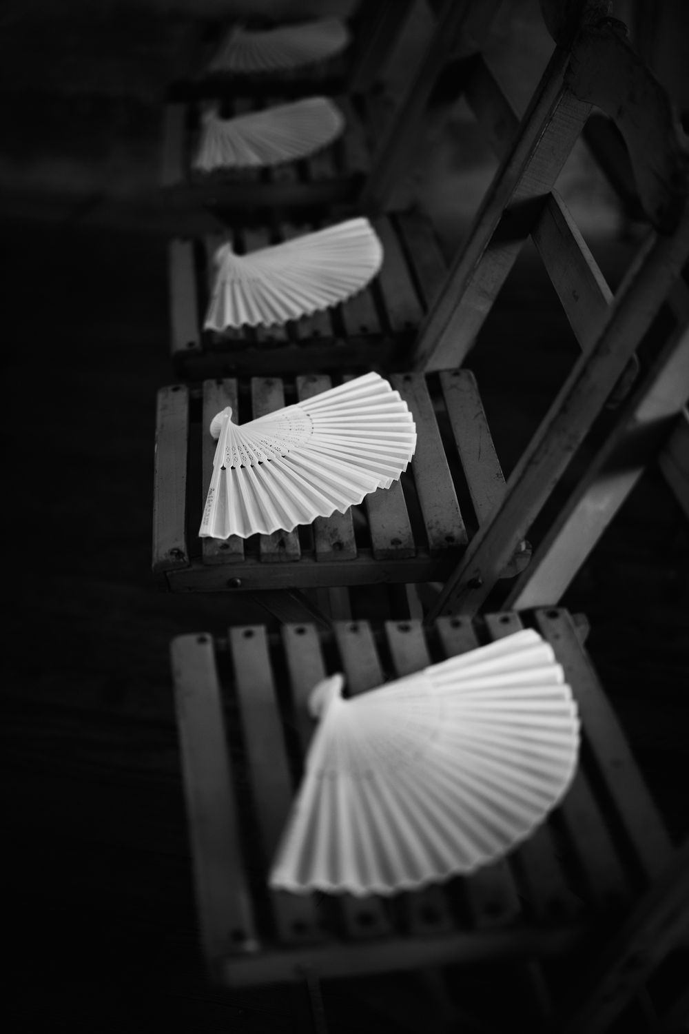 Artistic black and white detail shot of decorative paper fans in dramatic lighting.