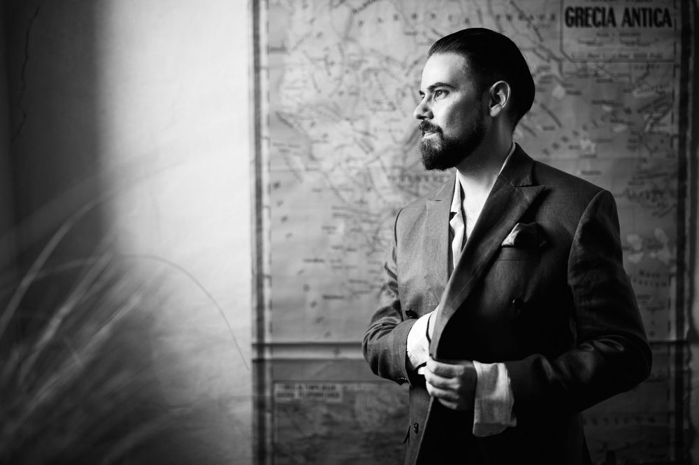 Dramatic black and white portrait series against textured brick wall in moody lighting.
