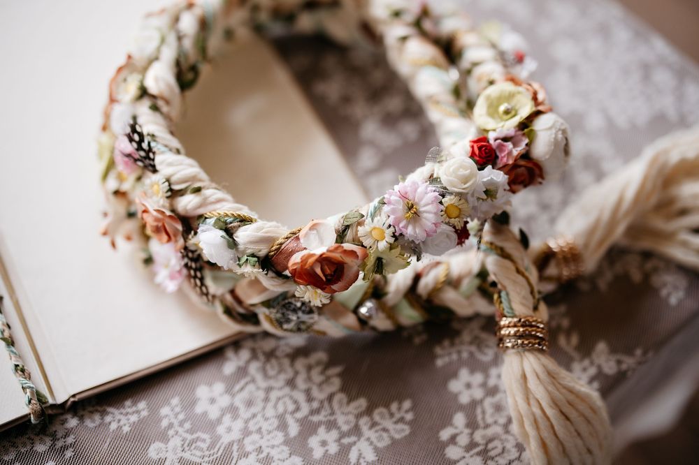 A delicate floral crown made with dried flowers and roses in soft pastel colors rests on lace fabric.