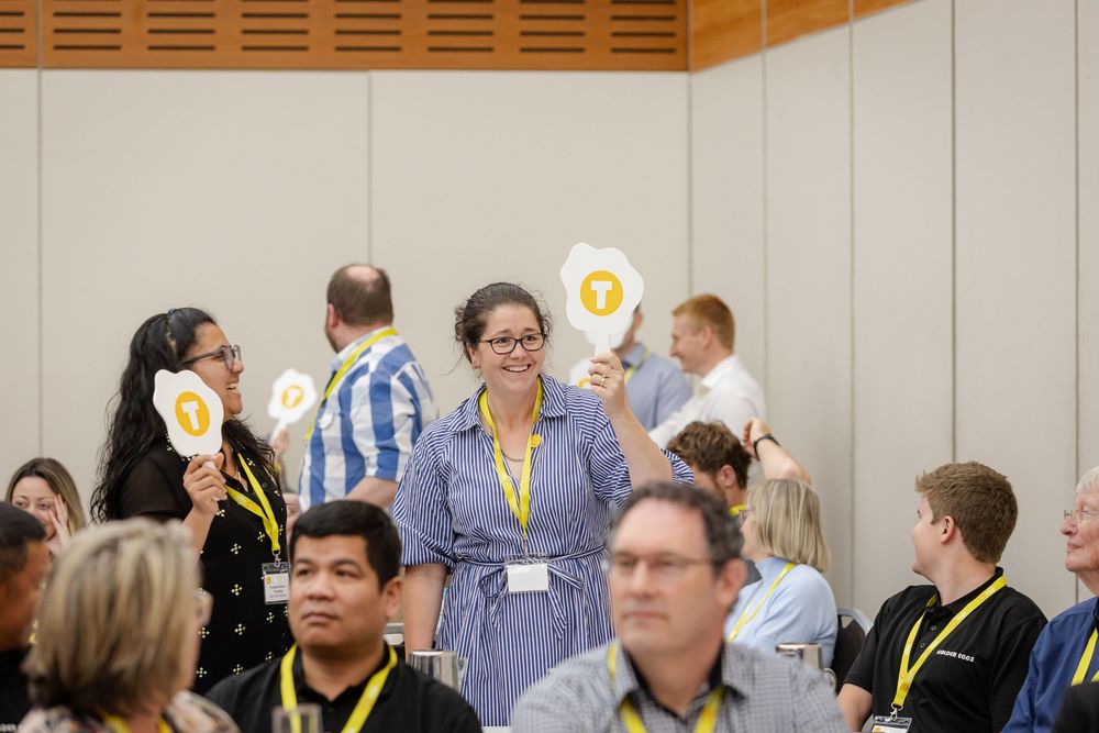Business professionals engage in discussion at round tables during a conference or workshop event.