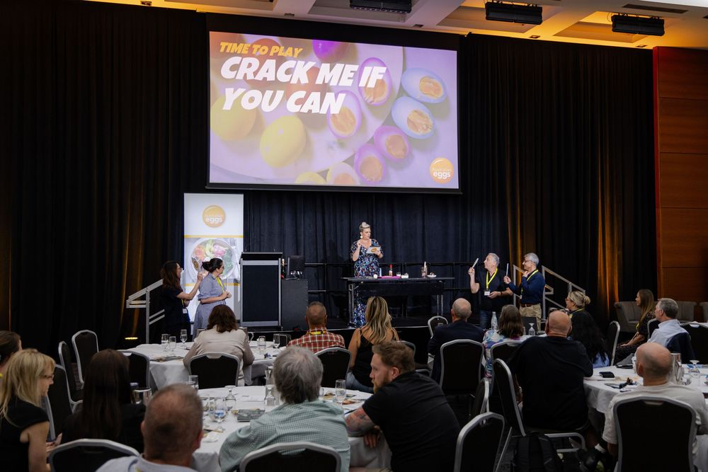 Kirsten Graham Photography captures a side view of conference room with projector screen showing presentation content and audience seating.