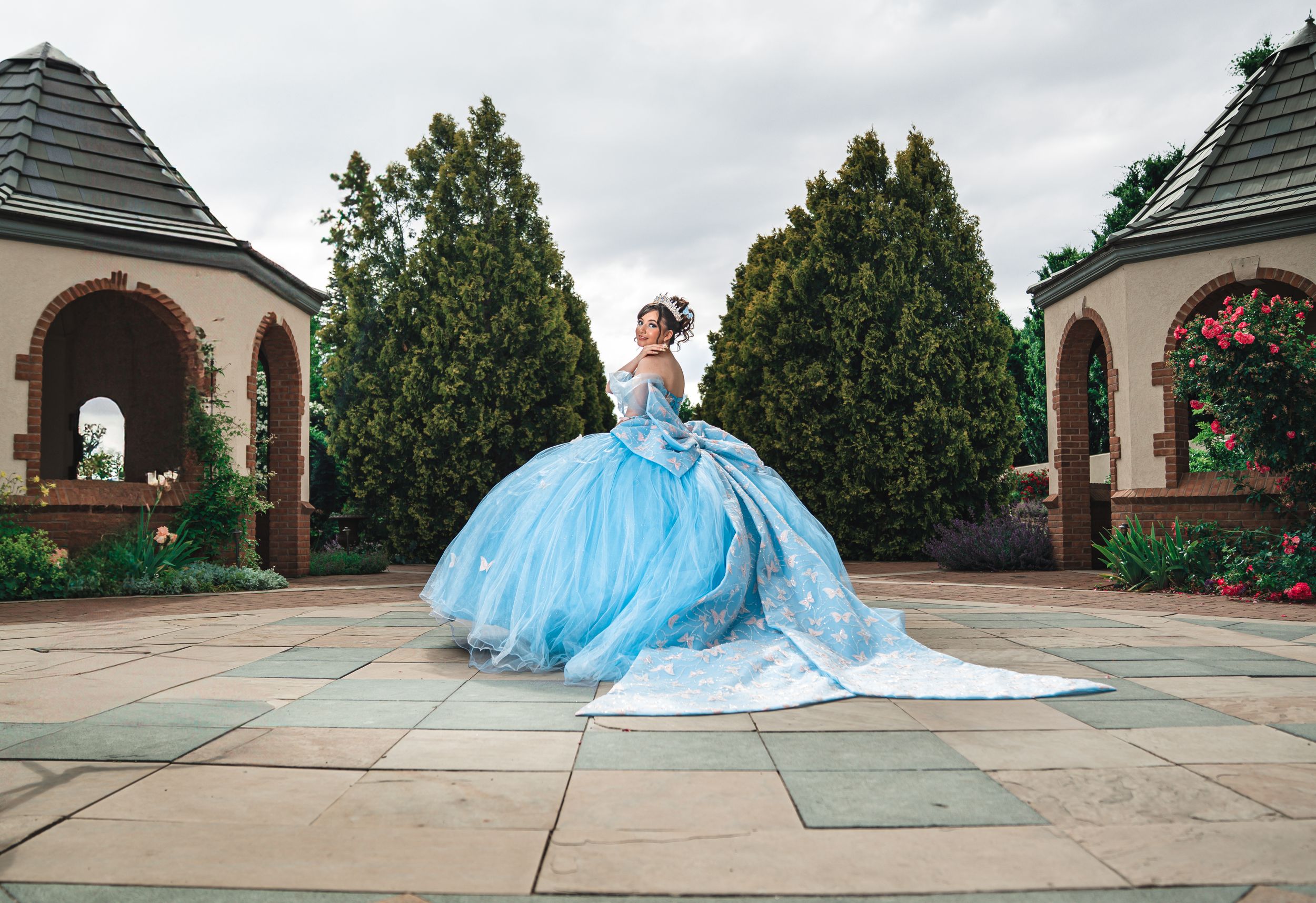 A blue ballgown flows elegantly across a stone courtyard in a series of connected photos.