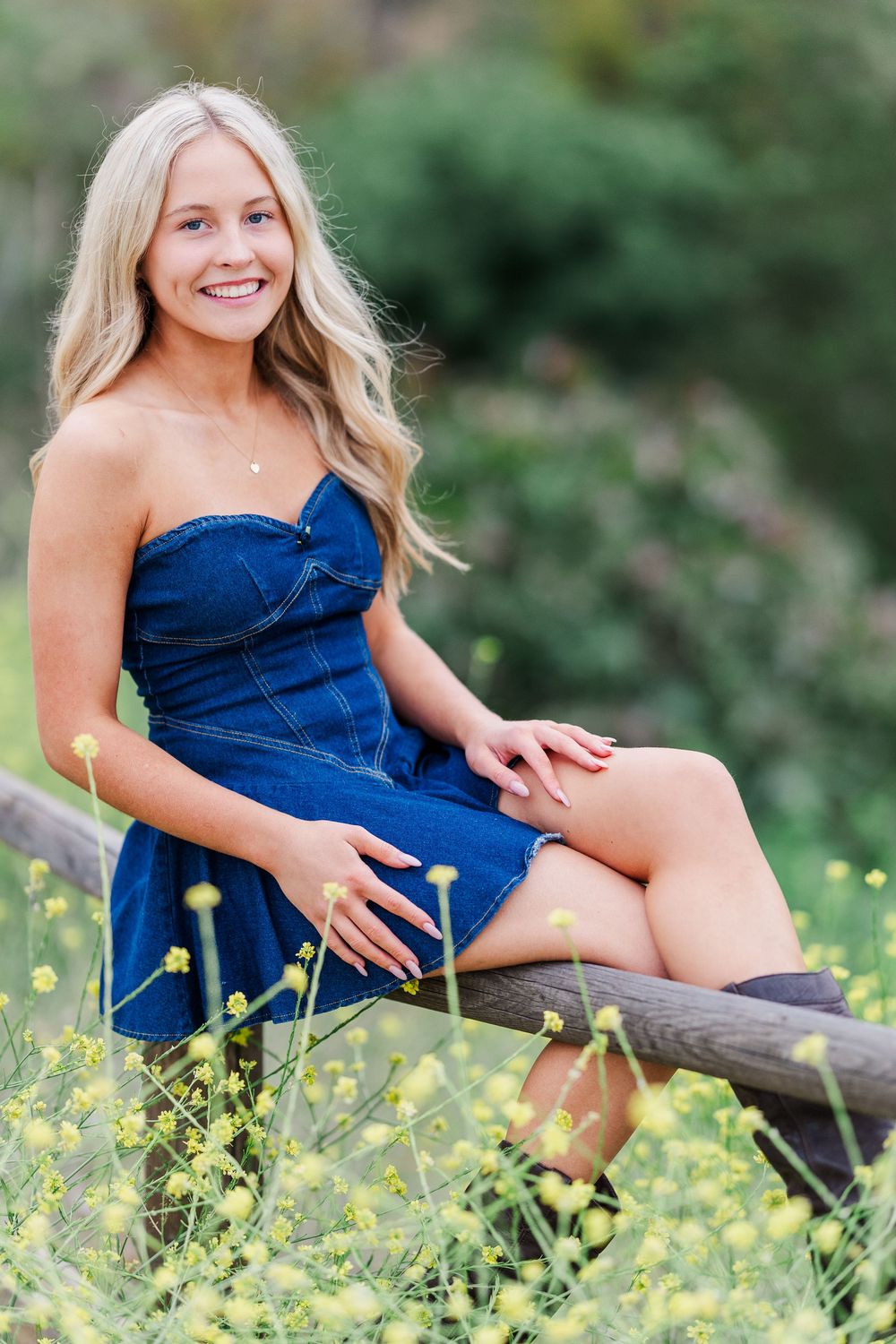 A series of outdoor portraits in a blue dress sitting on a log surrounded by yellow wildflowers in a natural setting.