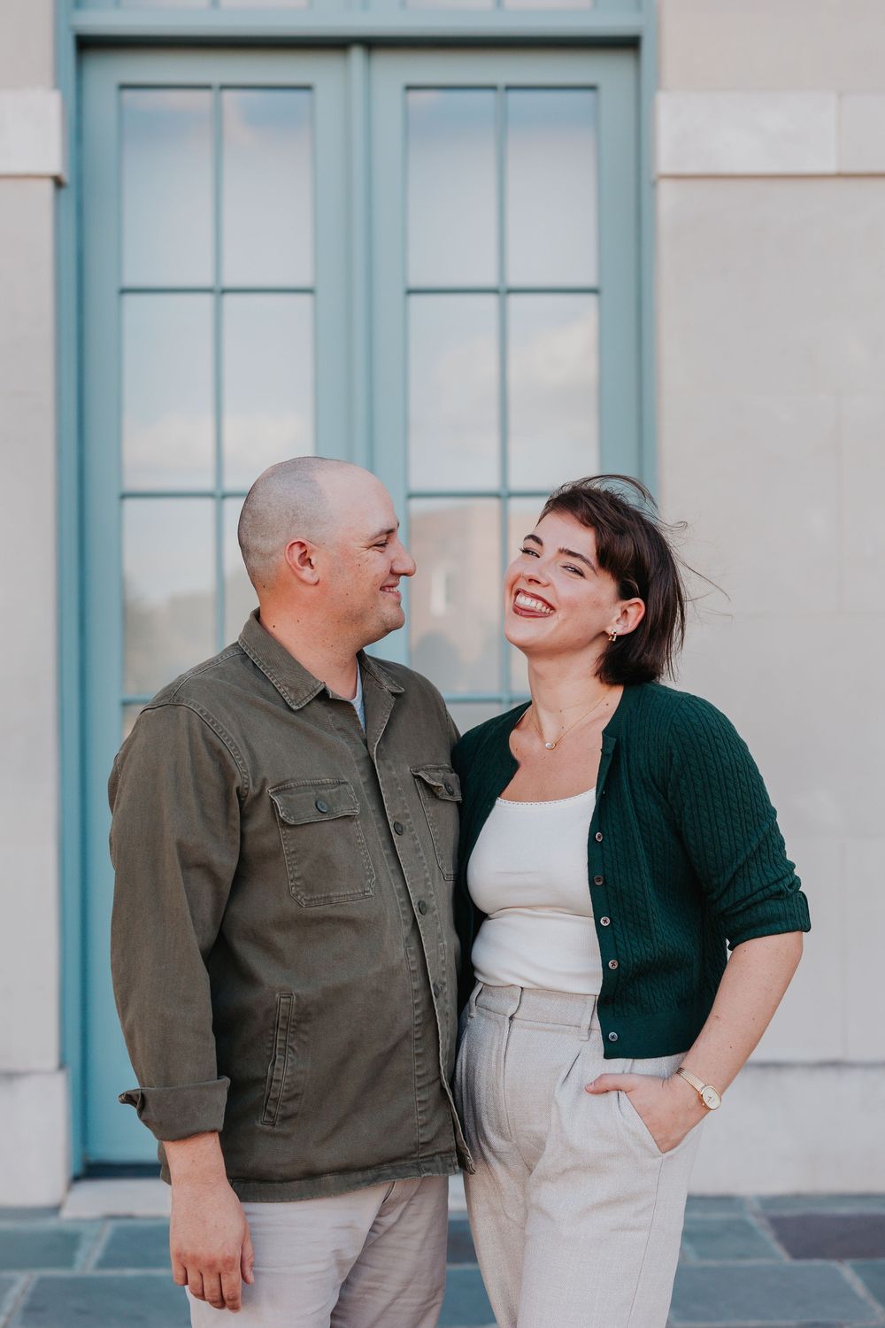 Couple sharing a candid moment in front of light blue door.