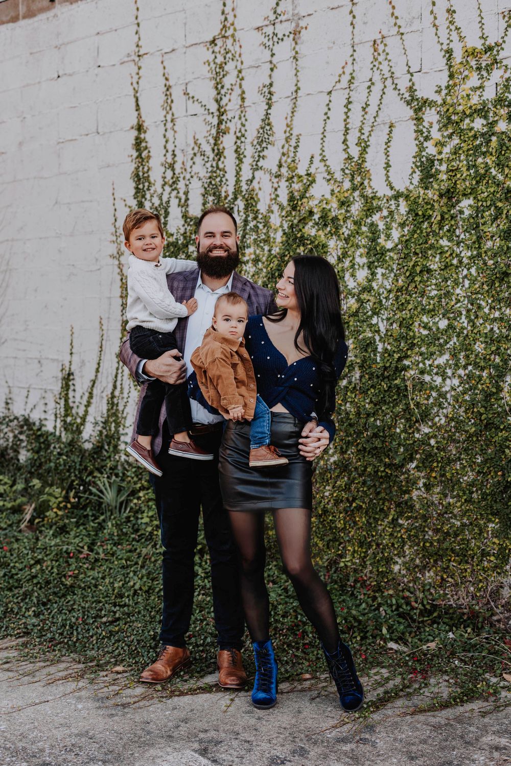 Candid family moment captured against white wall with climbing greenery.