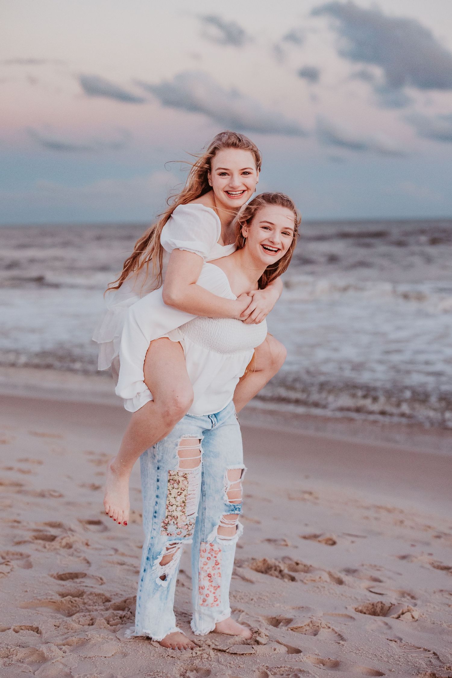 Playful beach photography session with distressed denim and white tops at sunset.