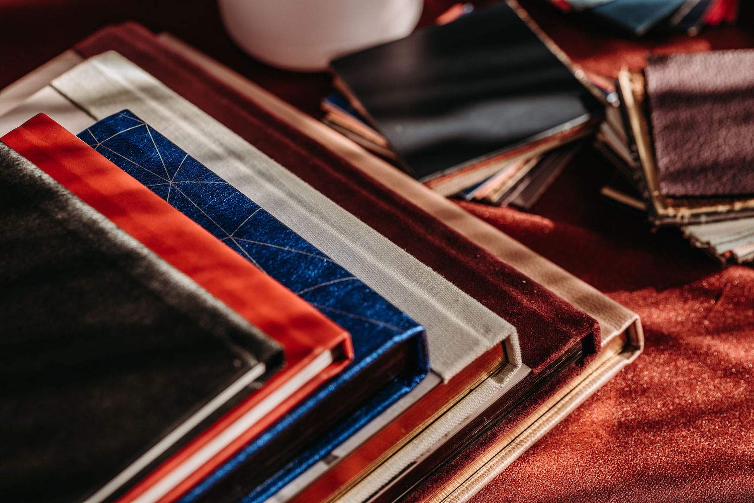Stacks of red and blue framed photos or artwork arranged in a diagonal pattern on a textured burgundy surface.